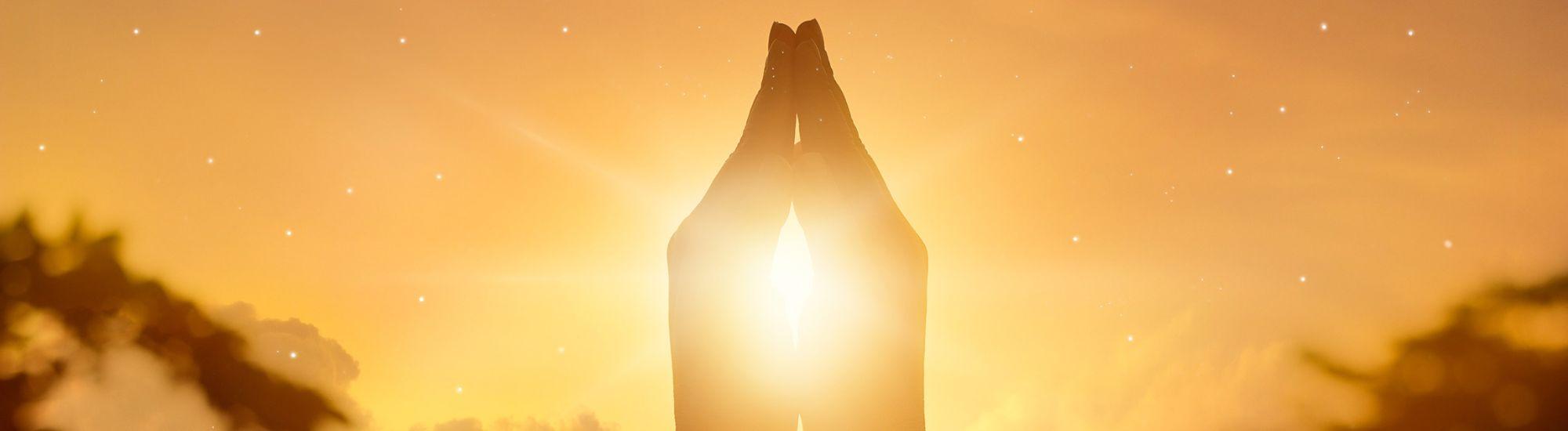 hands in prayer with sun shining through